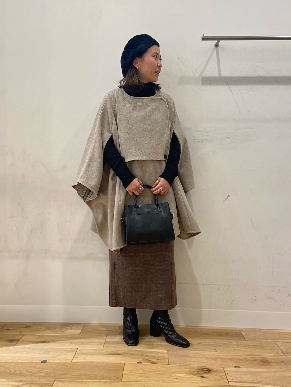 ブラック系のブーツ、ブラウン系のスカート、ブラック系のショルダーバッグを着用したレディースの冬コーディネートの3枚目の写真