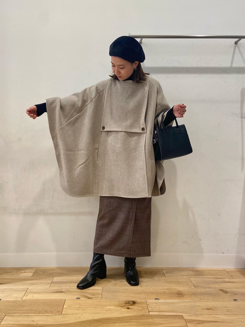 ブラック系のブーツ、ブラウン系のスカート、ブラック系のショルダーバッグを着用したレディースの冬コーディネートの2枚目の写真