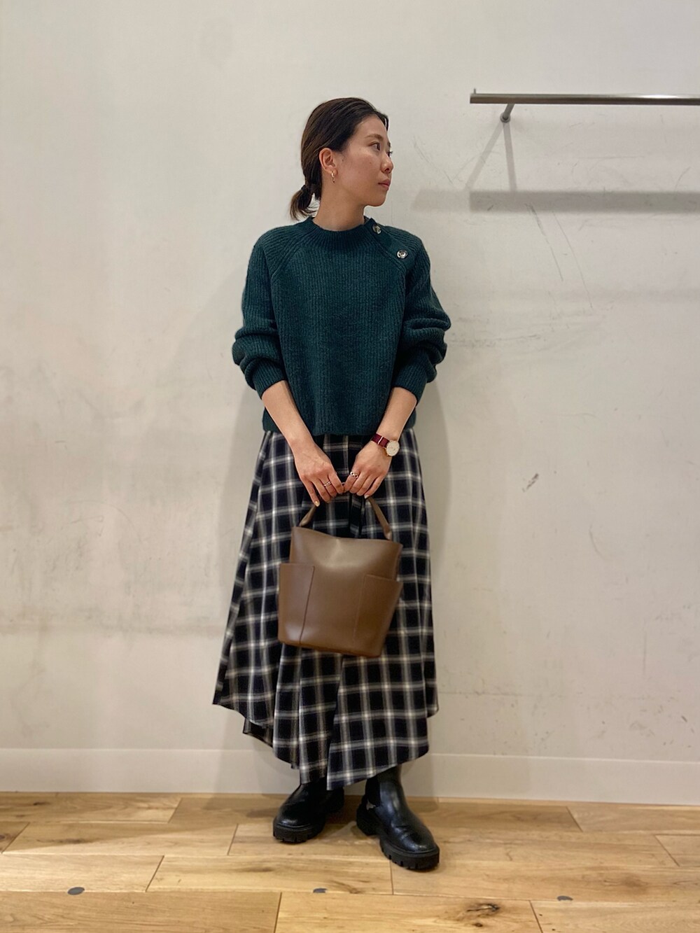 ブラウン系のショルダーバッグ、グリーン系のニット/セーター、ブラック系のスカートを着用したレディースの冬コーディネートの3枚目の写真