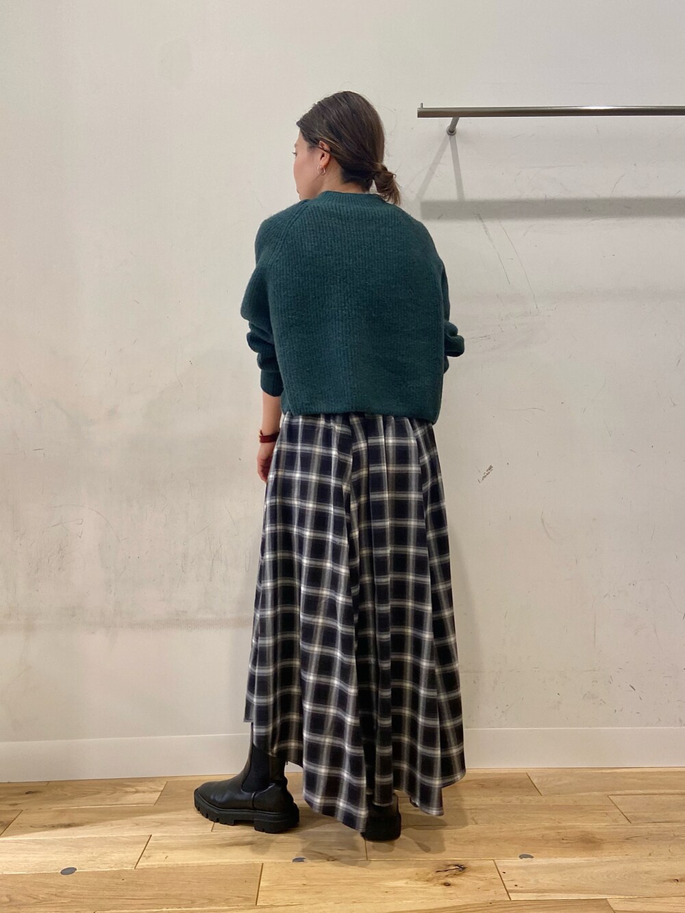 ブラウン系のショルダーバッグ、グリーン系のニット/セーター、ブラック系のスカートを着用したレディースの冬コーディネートの2枚目の写真