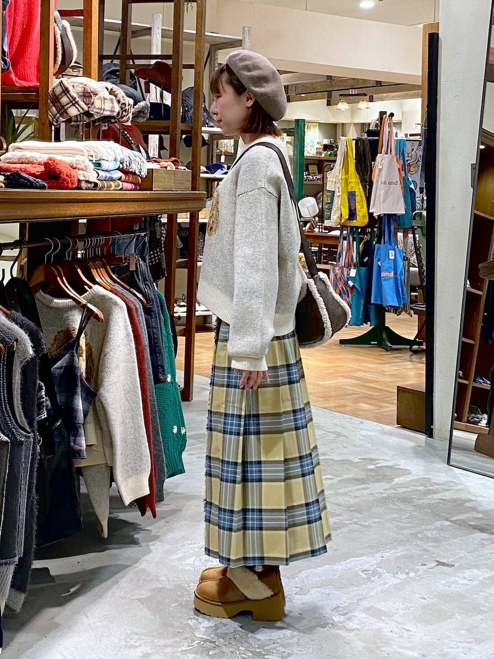 ベージュ系のスカート、イエロー系のブーツ、ブラウン系のショルダーバッグを着用したレディースの秋コーディネートの2枚目の写真