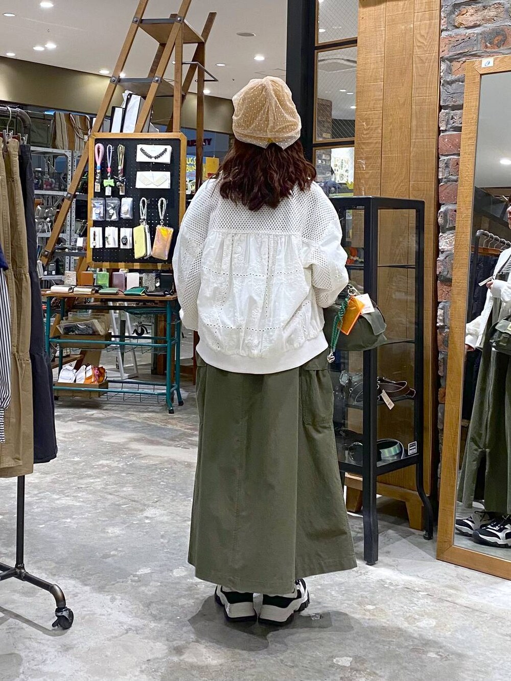 ホワイト系のTシャツ/カットソー、グリーン系のジャンパースカート、ブラック系のスニーカーを着用したレディースの春コーディネートの3枚目の写真