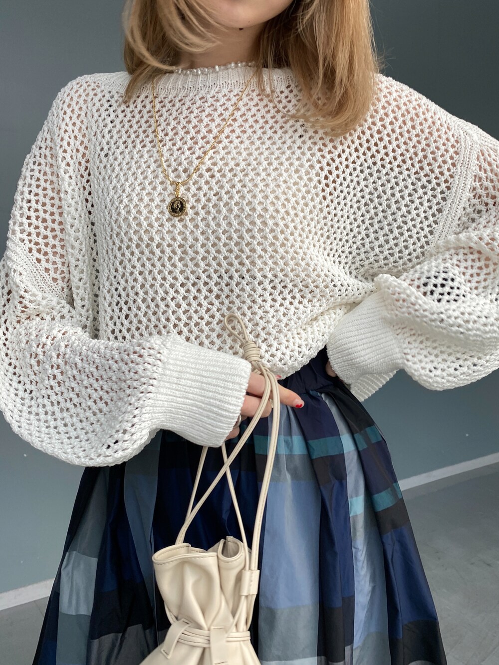 ホワイト系のニット/セーター、ホワイト系のスカート、ベージュ系のショルダーバッグを着用したレディースの冬コーディネートの5枚目の写真