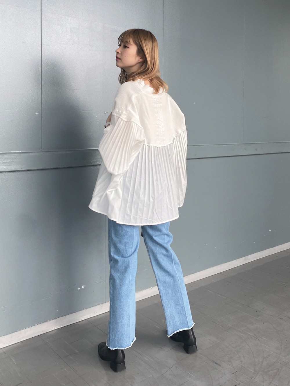 ホワイト系のニット/セーター、ブルー系のデニムパンツ、ブラック系のショルダーバッグを着用したレディースの冬コーディネートの2枚目の写真