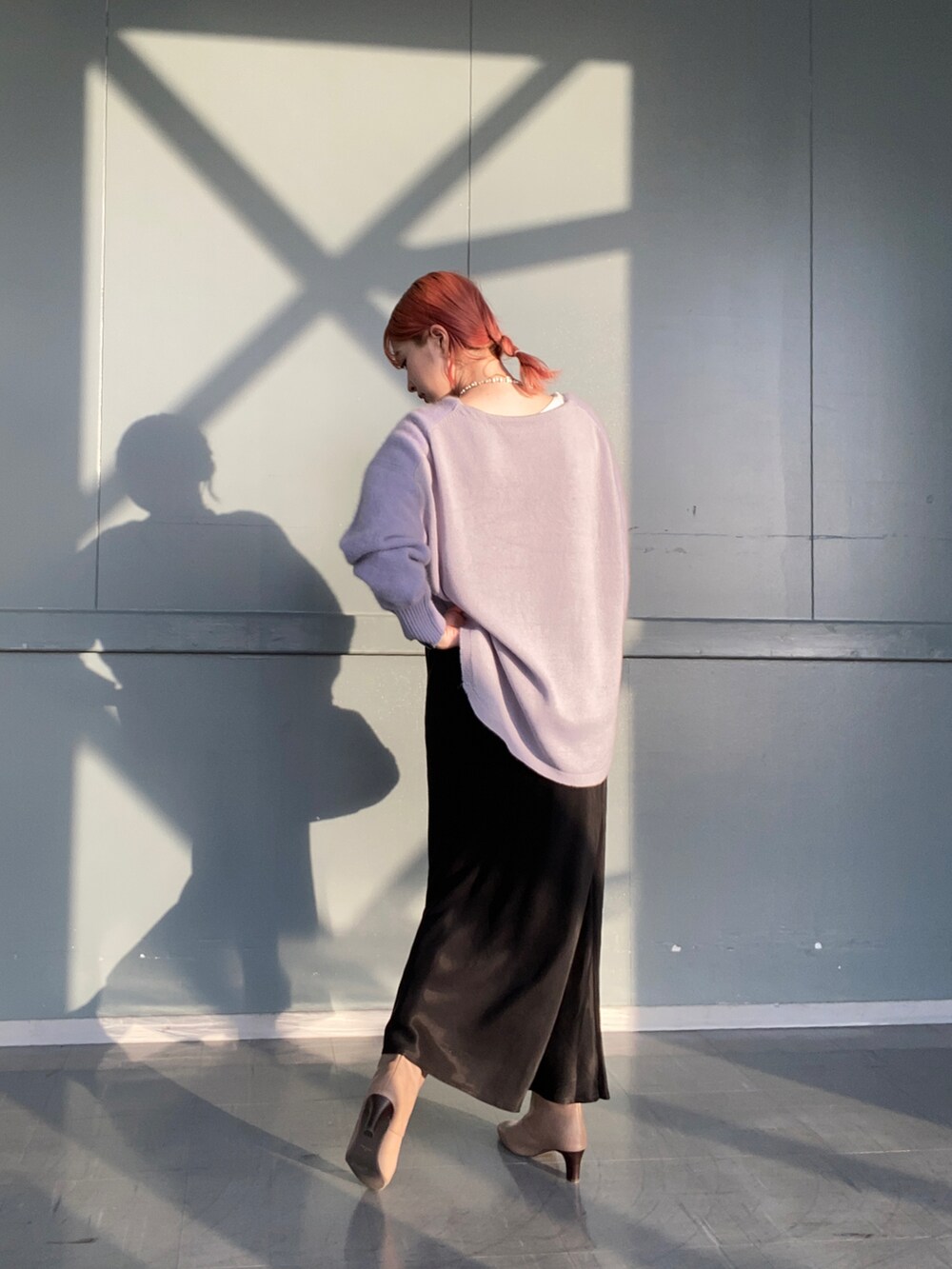 パープル系のニット/セーター、ベージュ系のハンドバッグ、ブラック系のスカートを着用したレディースの冬コーディネートの3枚目の写真