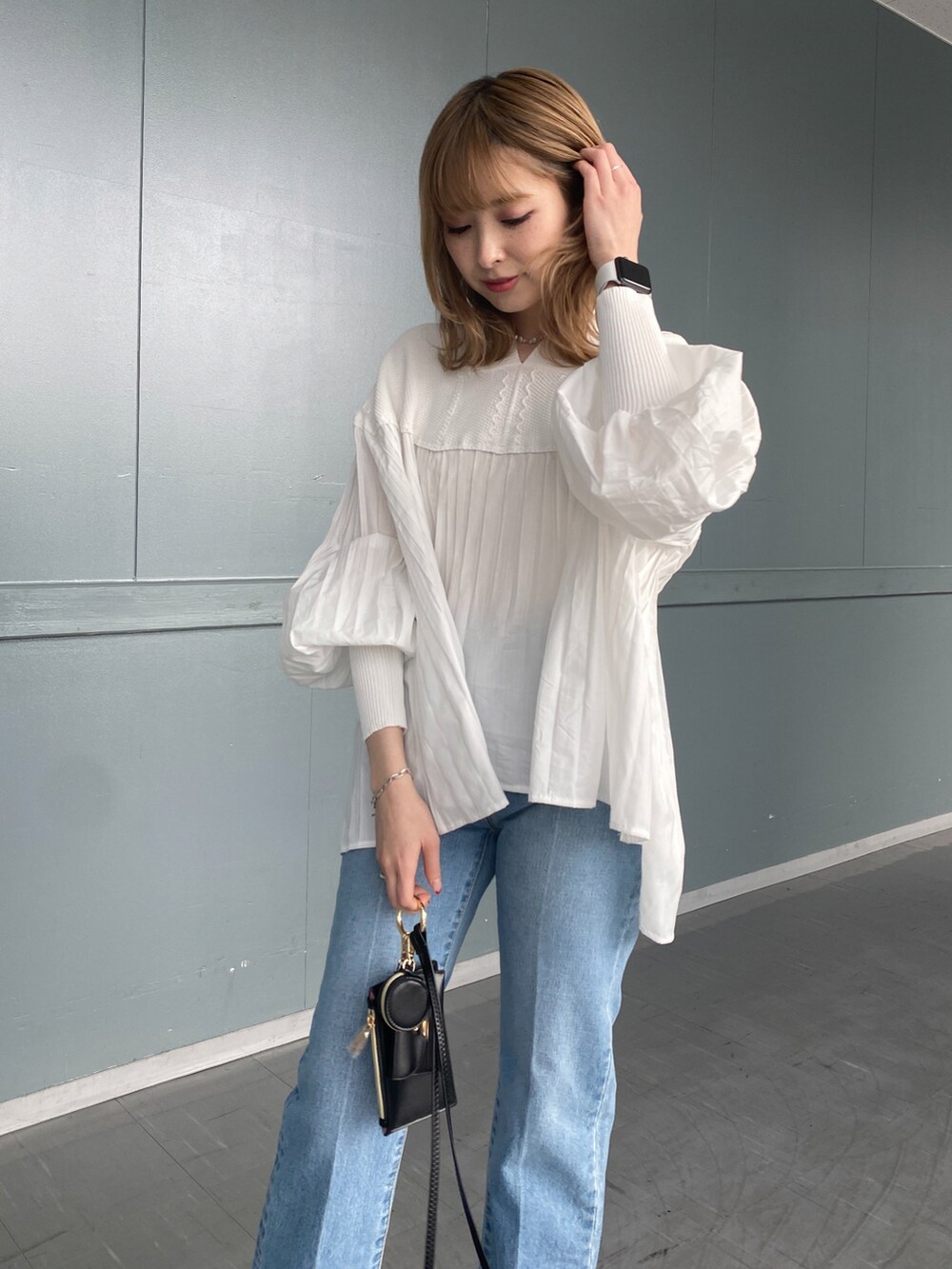 ホワイト系のニット/セーター、ブルー系のデニムパンツ、ブラック系のショルダーバッグを着用したレディースの冬コーディネートの4枚目の写真