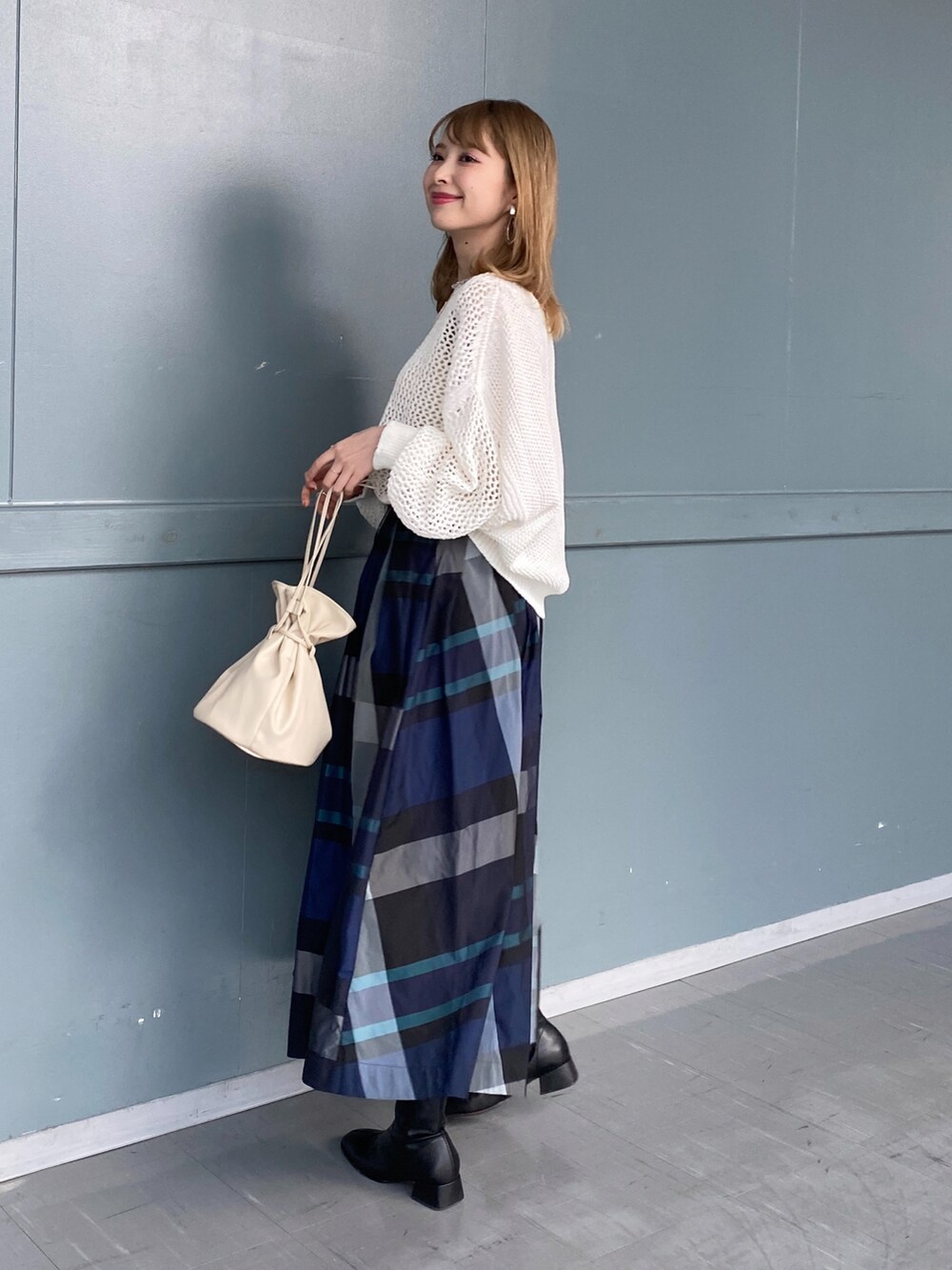 ホワイト系のニット/セーター、ホワイト系のスカート、ベージュ系のショルダーバッグを着用したレディースの冬コーディネートの2枚目の写真