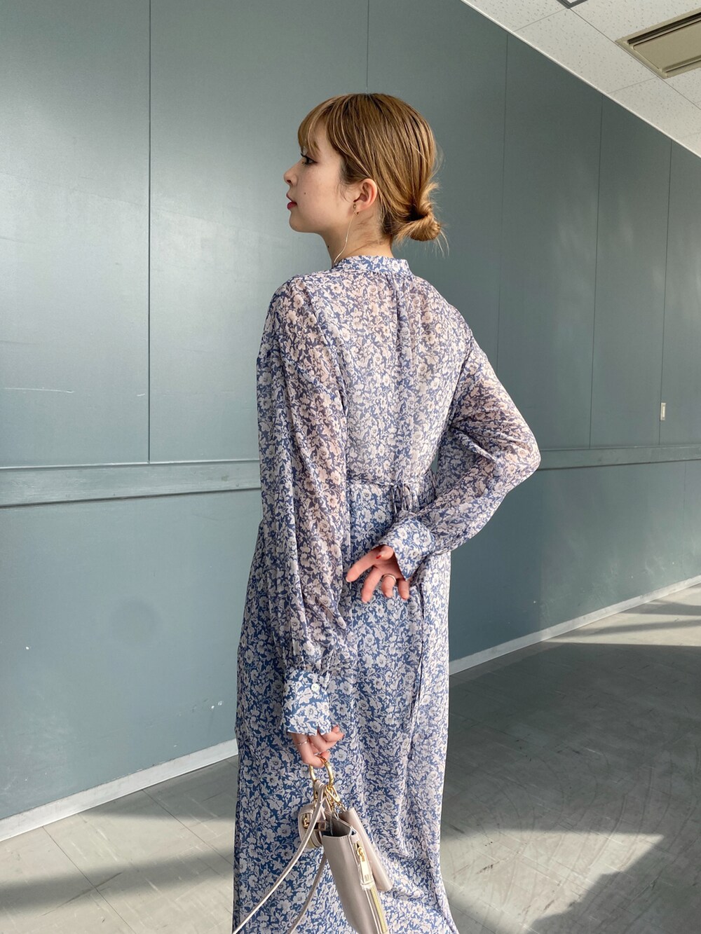 ブルー系のワンピース、ホワイト系のショルダーバッグ、ブルー系のデニムパンツを着用したレディースの冬コーディネートの4枚目の写真