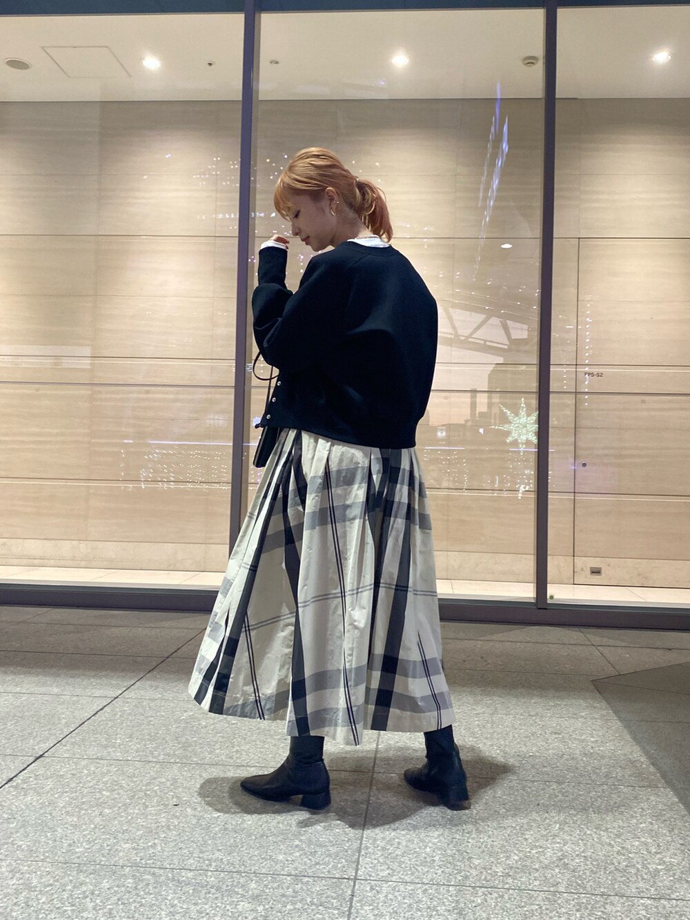 ブラック系のカーディガン/ボレロ、ホワイト系のスカート、ブラック系のショルダーバッグを着用したレディースの冬コーディネートの3枚目の写真