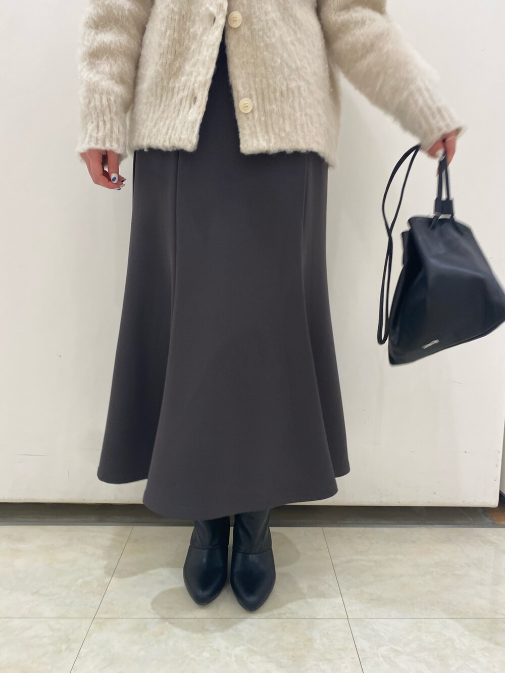 ベージュ系のニット/セーター、グレー系のスカート、ブラック系のブーツを着用したレディースの冬コーディネートの5枚目の写真