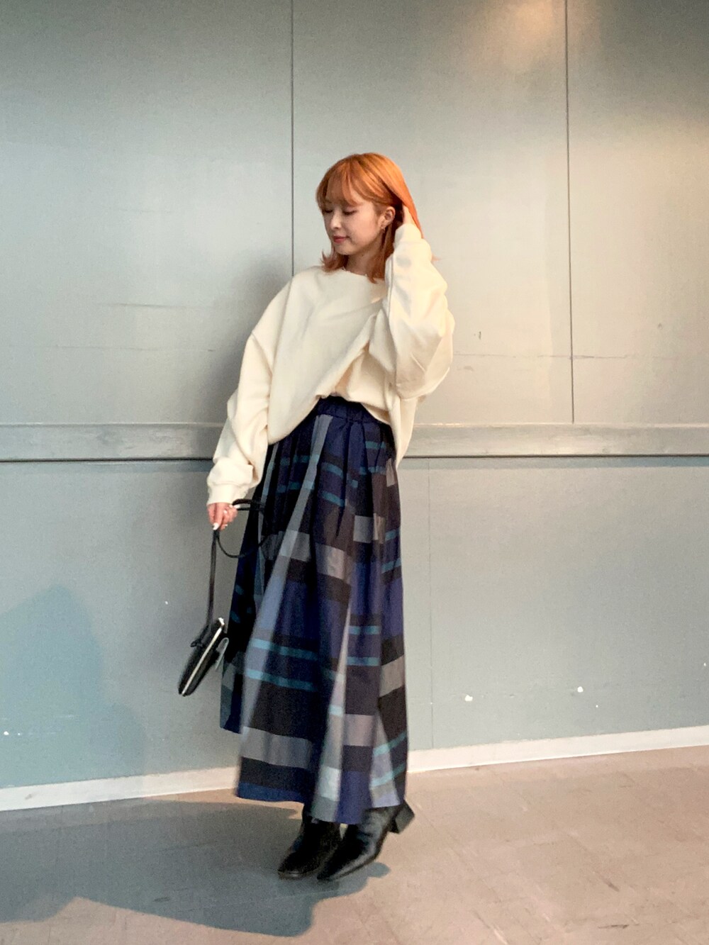 ホワイト系のTシャツ/カットソー、ブルー系のスカート、ブラック系のブーツを着用したレディースの冬コーディネートの2枚目の写真