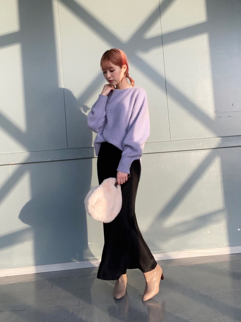 パープル系のニット/セーター、ベージュ系のハンドバッグ、ブラック系のスカートを着用したレディースの冬コーディネートの2枚目の写真