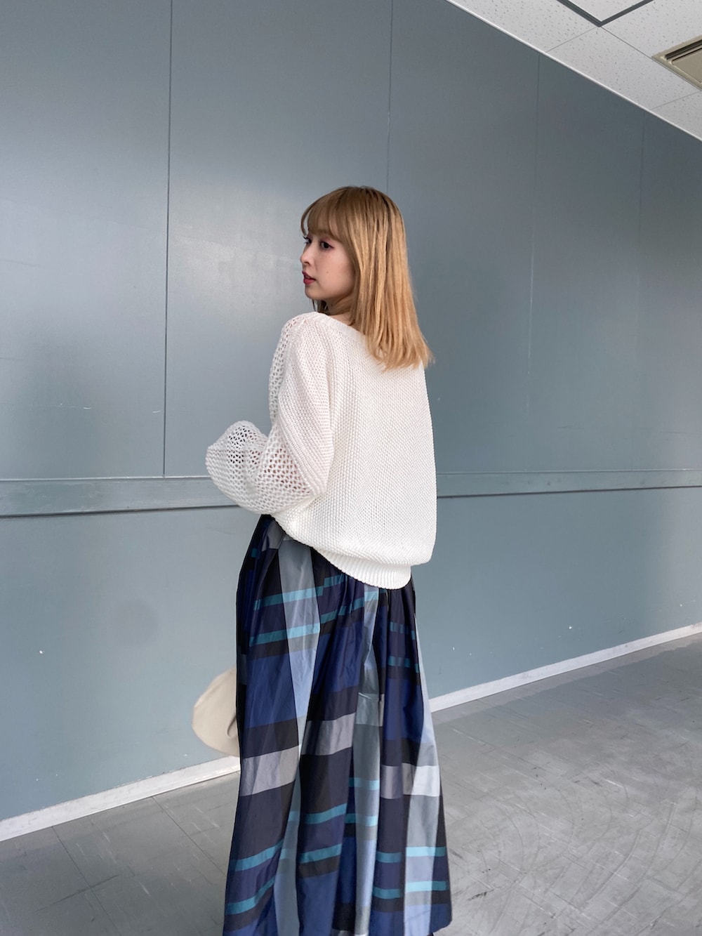 ホワイト系のニット/セーター、ホワイト系のスカート、ベージュ系のショルダーバッグを着用したレディースの冬コーディネートの4枚目の写真