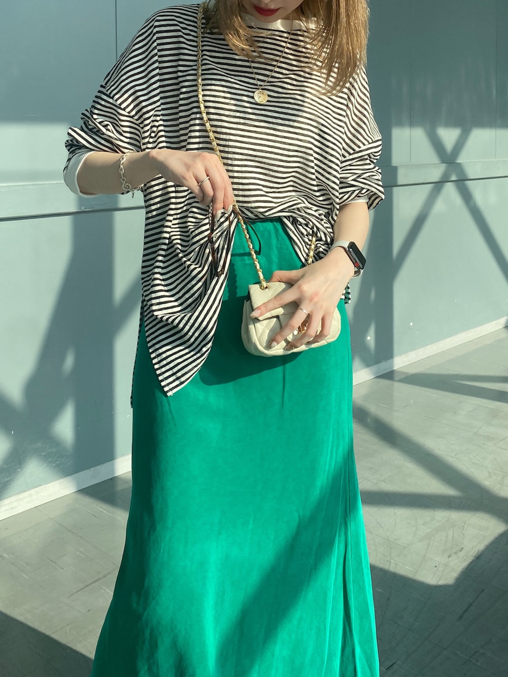 ブラック系のTシャツ/カットソー、グリーン系のスカート、ホワイト系のショルダーバッグを着用したレディースの春コーディネートの5枚目の写真