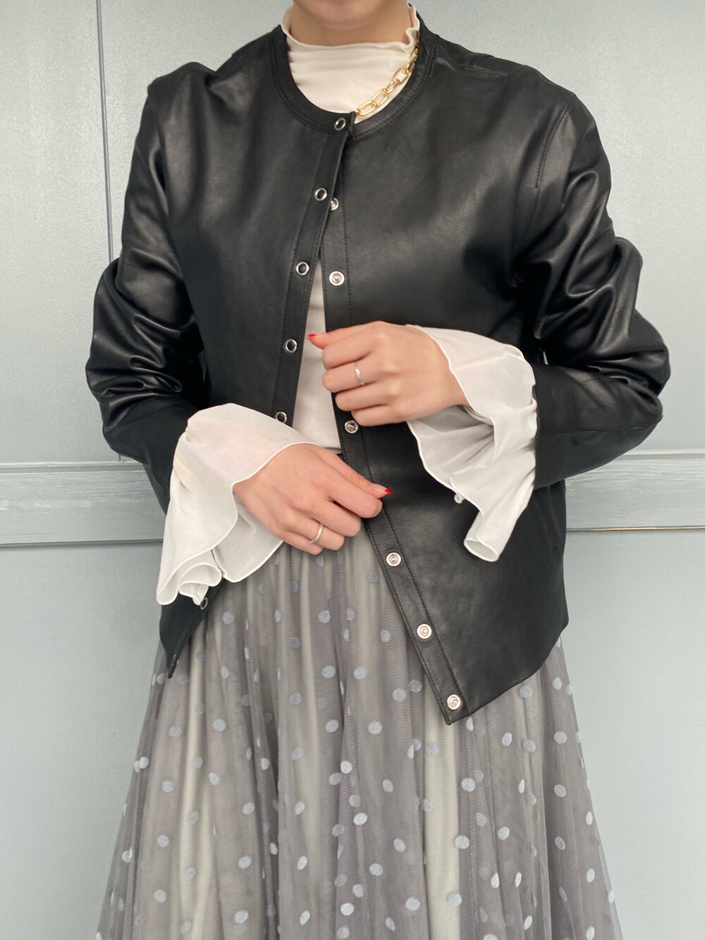 ホワイト系のTシャツ/カットソー、ブラック系のノーカラージャケット、グレー系のスカートを着用したレディースの冬コーディネートの5枚目の写真