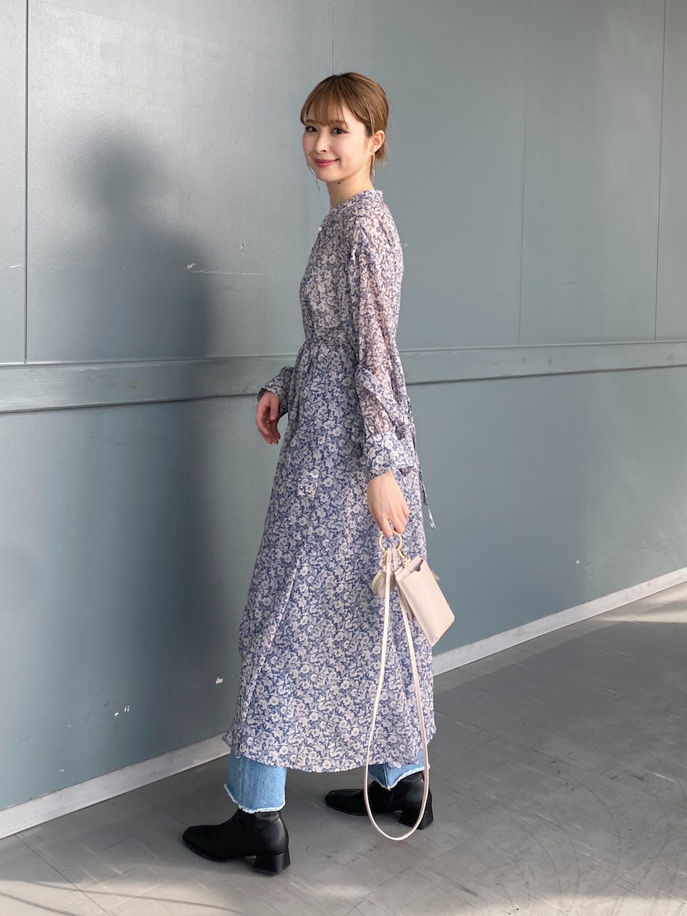 ブルー系のワンピース、ホワイト系のショルダーバッグ、ブルー系のデニムパンツを着用したレディースの冬コーディネートの2枚目の写真