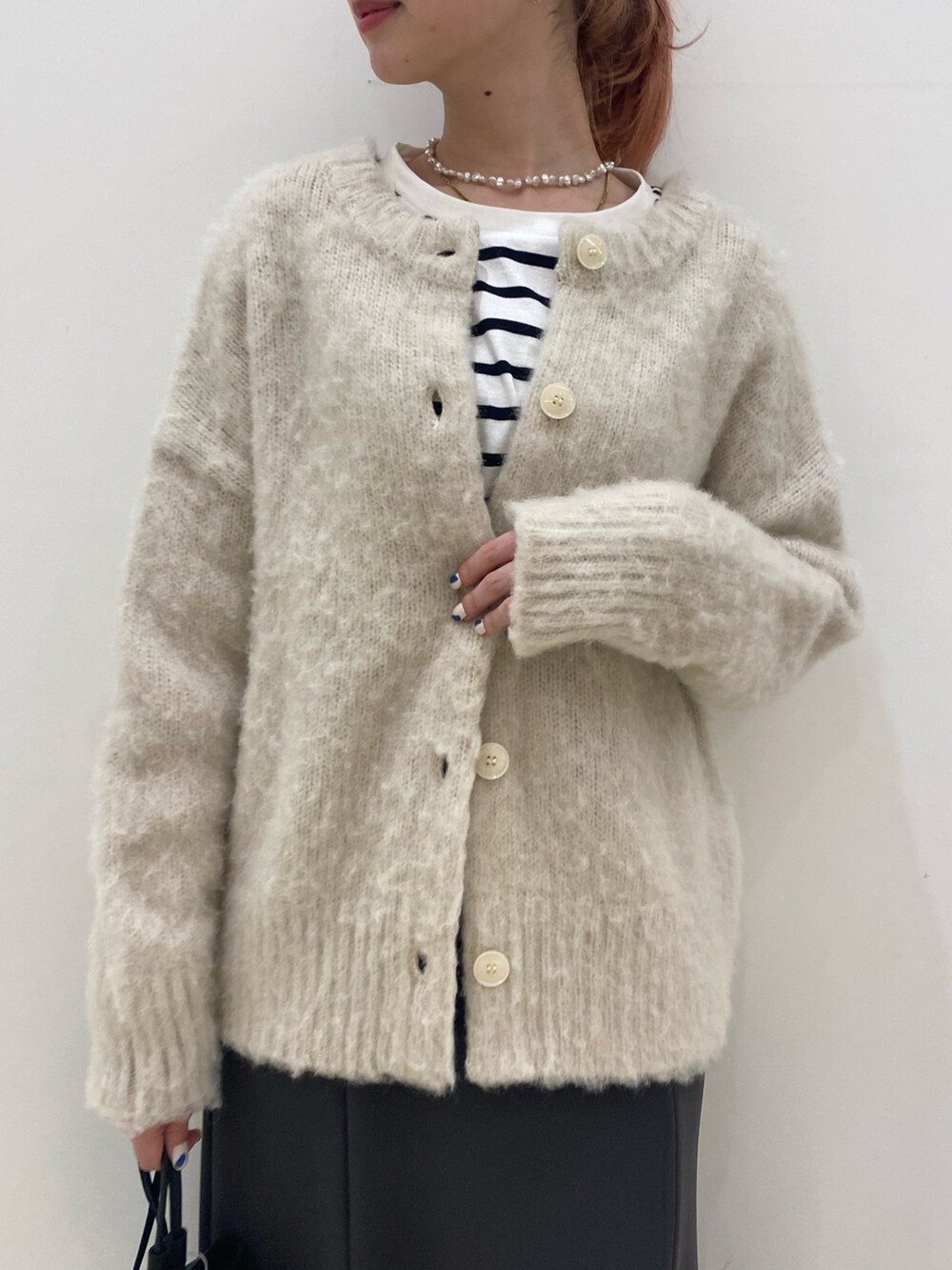 ベージュ系のニット/セーター、グレー系のスカート、ブラック系のブーツを着用したレディースの冬コーディネートの4枚目の写真