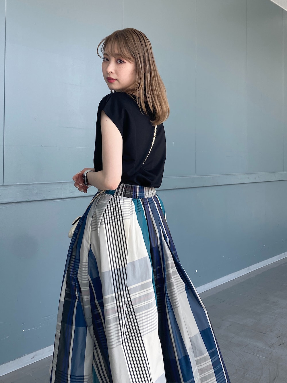 ブラック系のTシャツ/カットソー、グリーン系のスカート、ブラック系のサンダルを着用したレディースの春コーディネートの4枚目の写真