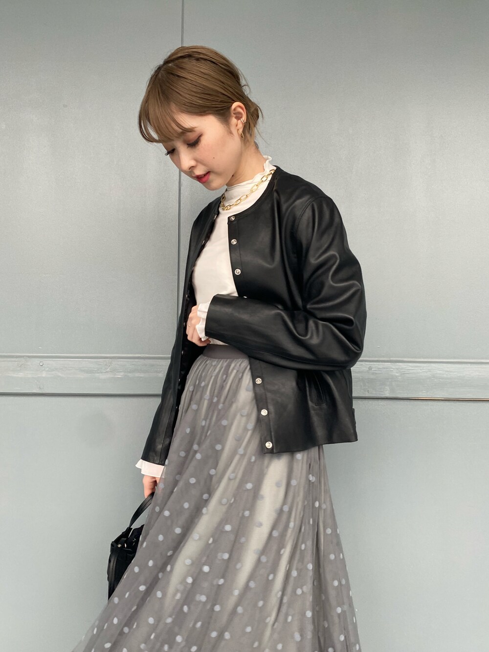 ホワイト系のTシャツ/カットソー、ブラック系のノーカラージャケット、グレー系のスカートを着用したレディースの冬コーディネートの4枚目の写真