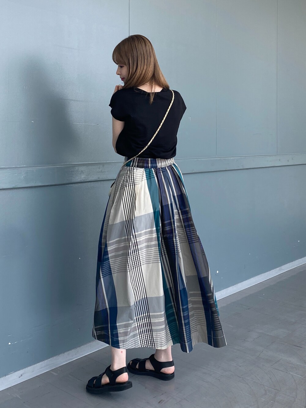 ブラック系のTシャツ/カットソー、グリーン系のスカート、ブラック系のサンダルを着用したレディースの春コーディネートの3枚目の写真