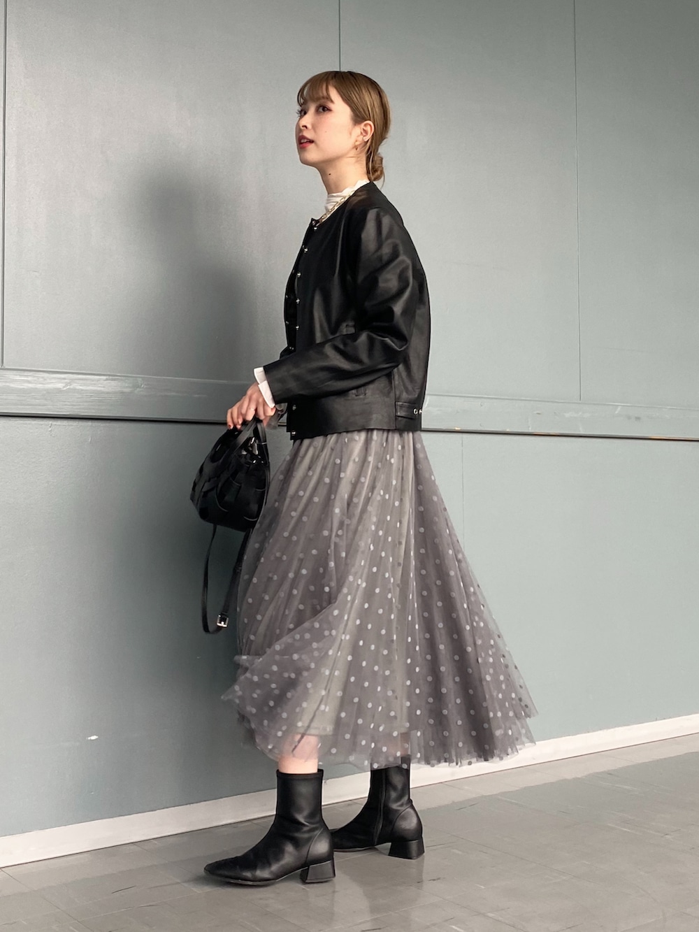 ホワイト系のTシャツ/カットソー、ブラック系のノーカラージャケット、グレー系のスカートを着用したレディースの冬コーディネートの2枚目の写真