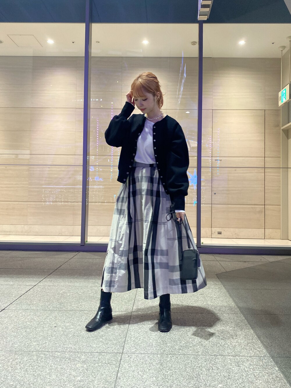 ブラック系のカーディガン/ボレロ、ホワイト系のスカート、ブラック系のショルダーバッグを着用したレディースの冬コーディネートの2枚目の写真