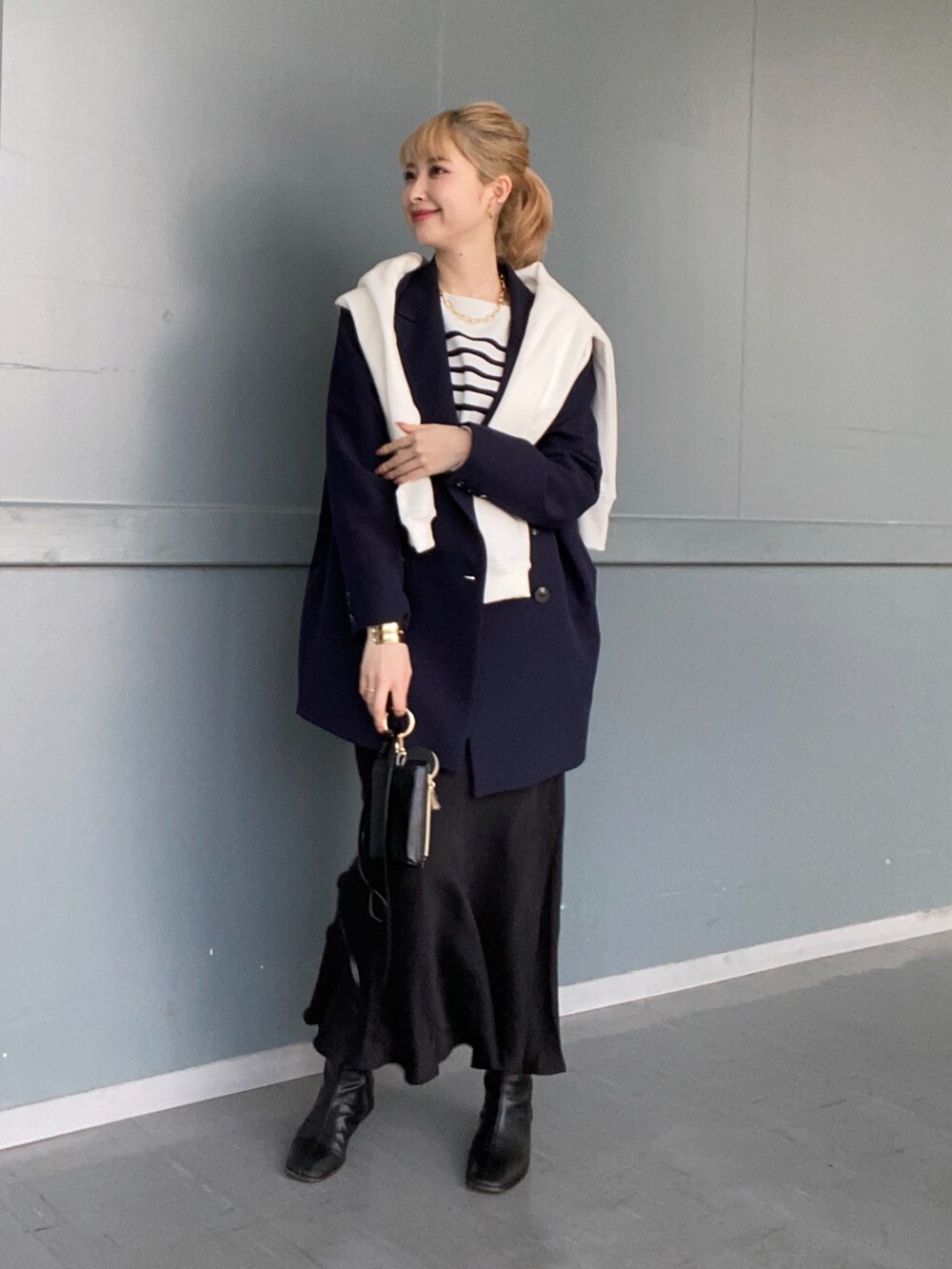ブラック系のニット/セーター、ブルー系のテーラードジャケット、ブラック系のスカートを着用したレディースの冬コーディネートの2枚目の写真