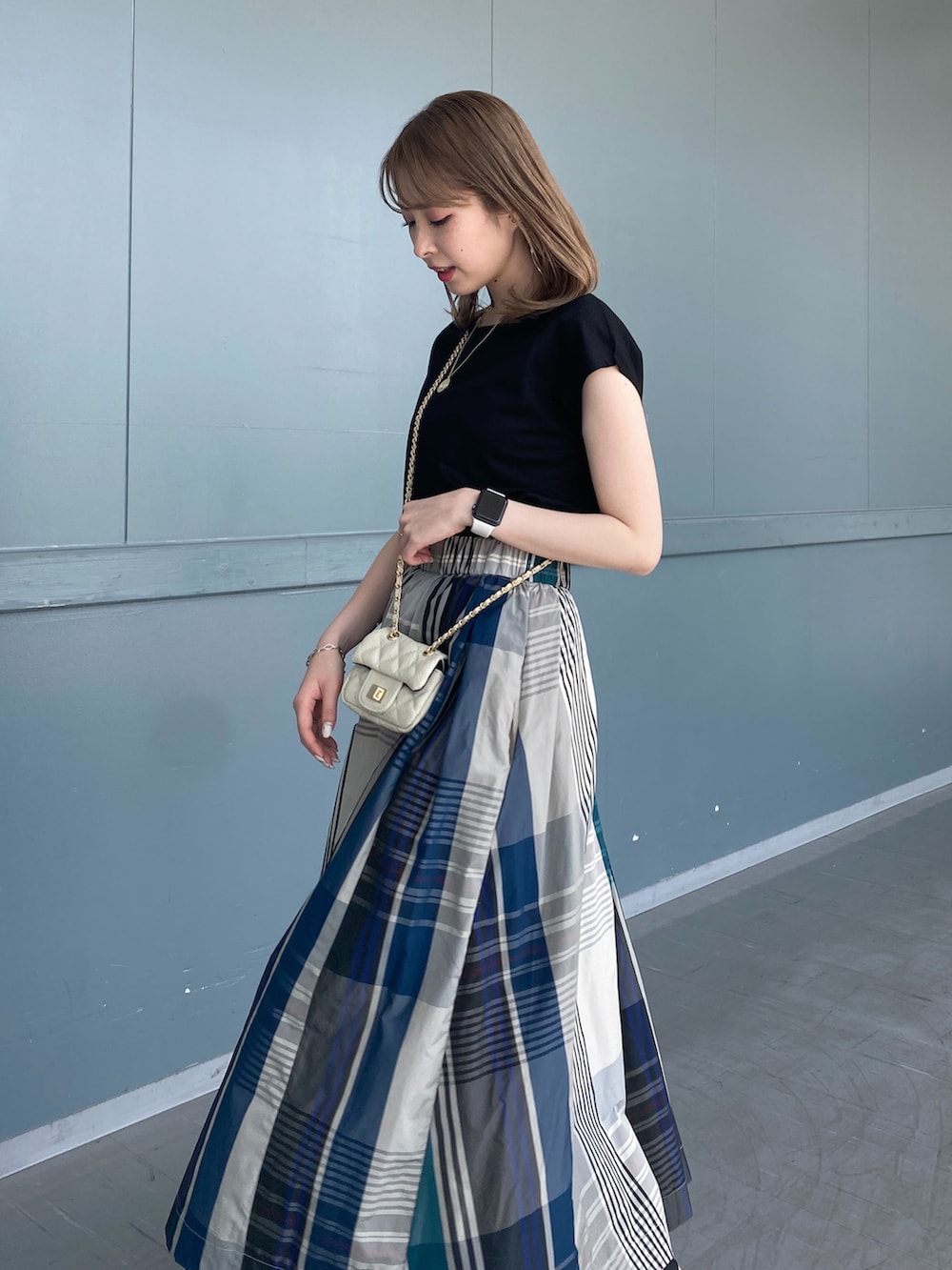 ブラック系のTシャツ/カットソー、グリーン系のスカート、ブラック系のサンダルを着用したレディースの春コーディネートの5枚目の写真