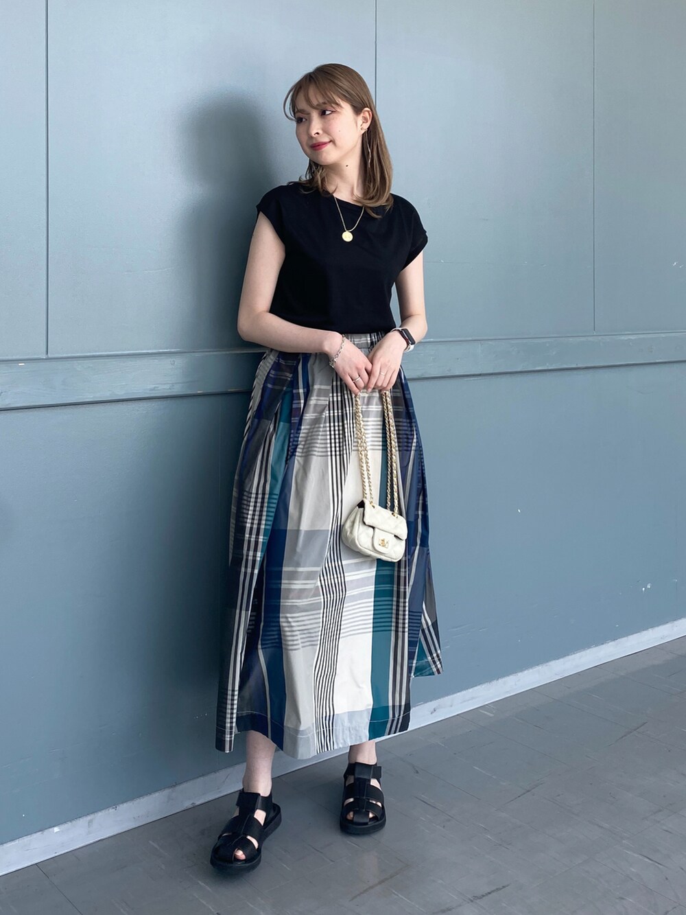 ブラック系のTシャツ/カットソー、グリーン系のスカート、ブラック系のサンダルを着用したレディースの春コーディネートの2枚目の写真