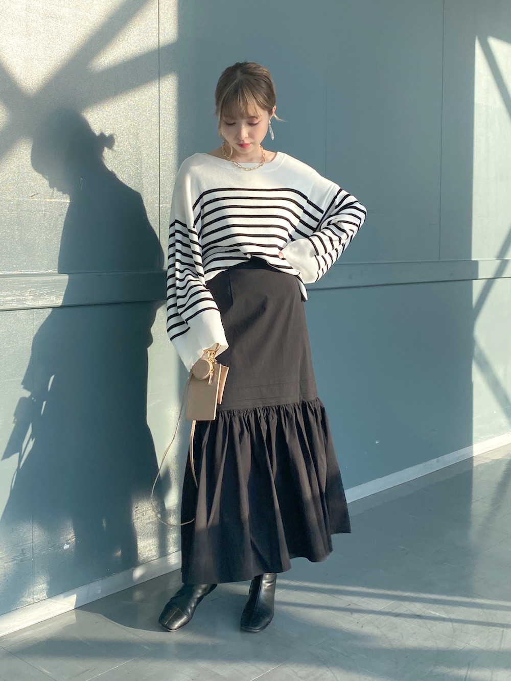 ブラック系のニット/セーター、ブラック系のスカート、ベージュ系のショルダーバッグを着用したレディースの冬コーディネートの2枚目の写真