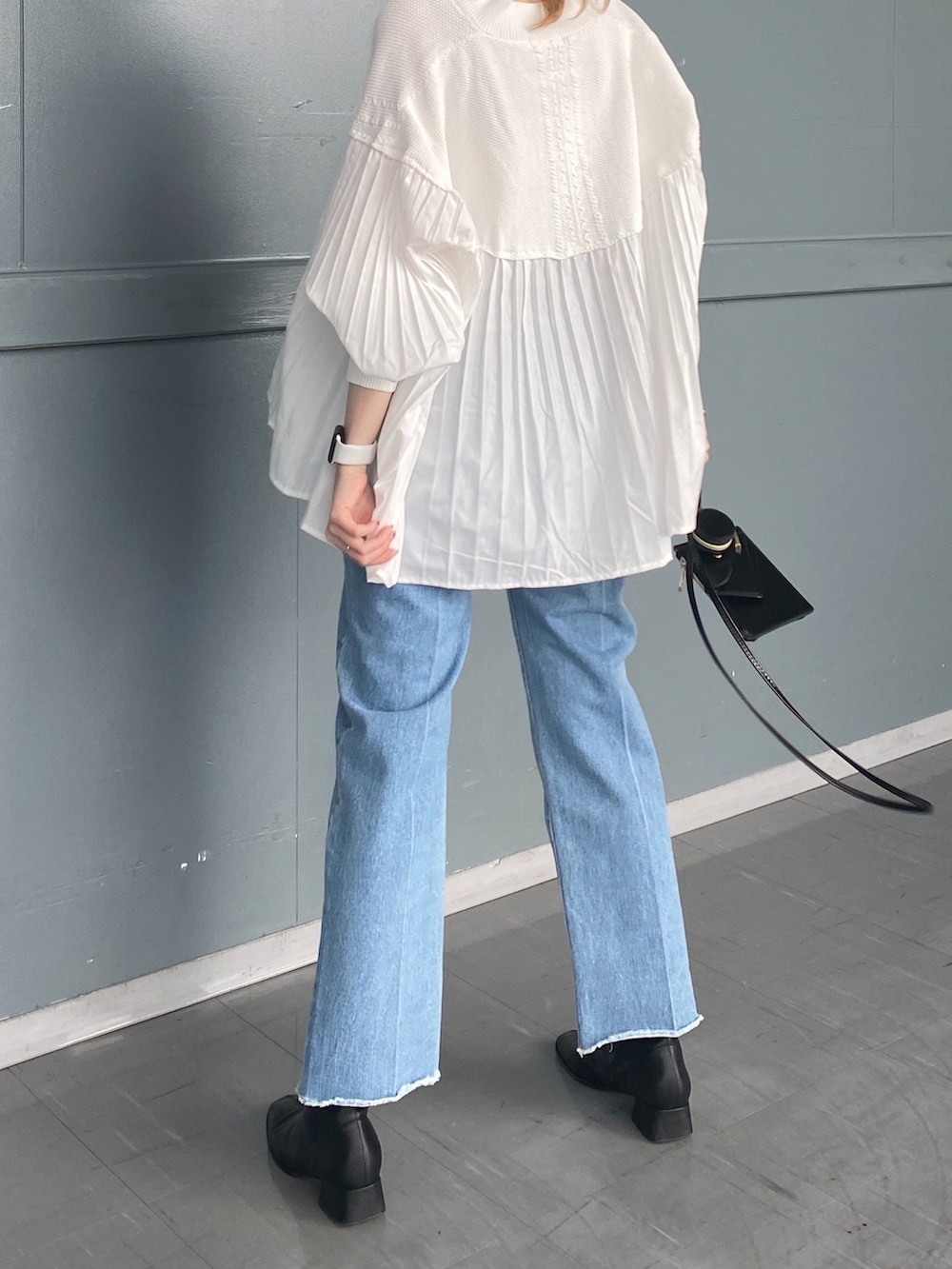 ホワイト系のニット/セーター、ブルー系のデニムパンツ、ブラック系のショルダーバッグを着用したレディースの冬コーディネートの3枚目の写真