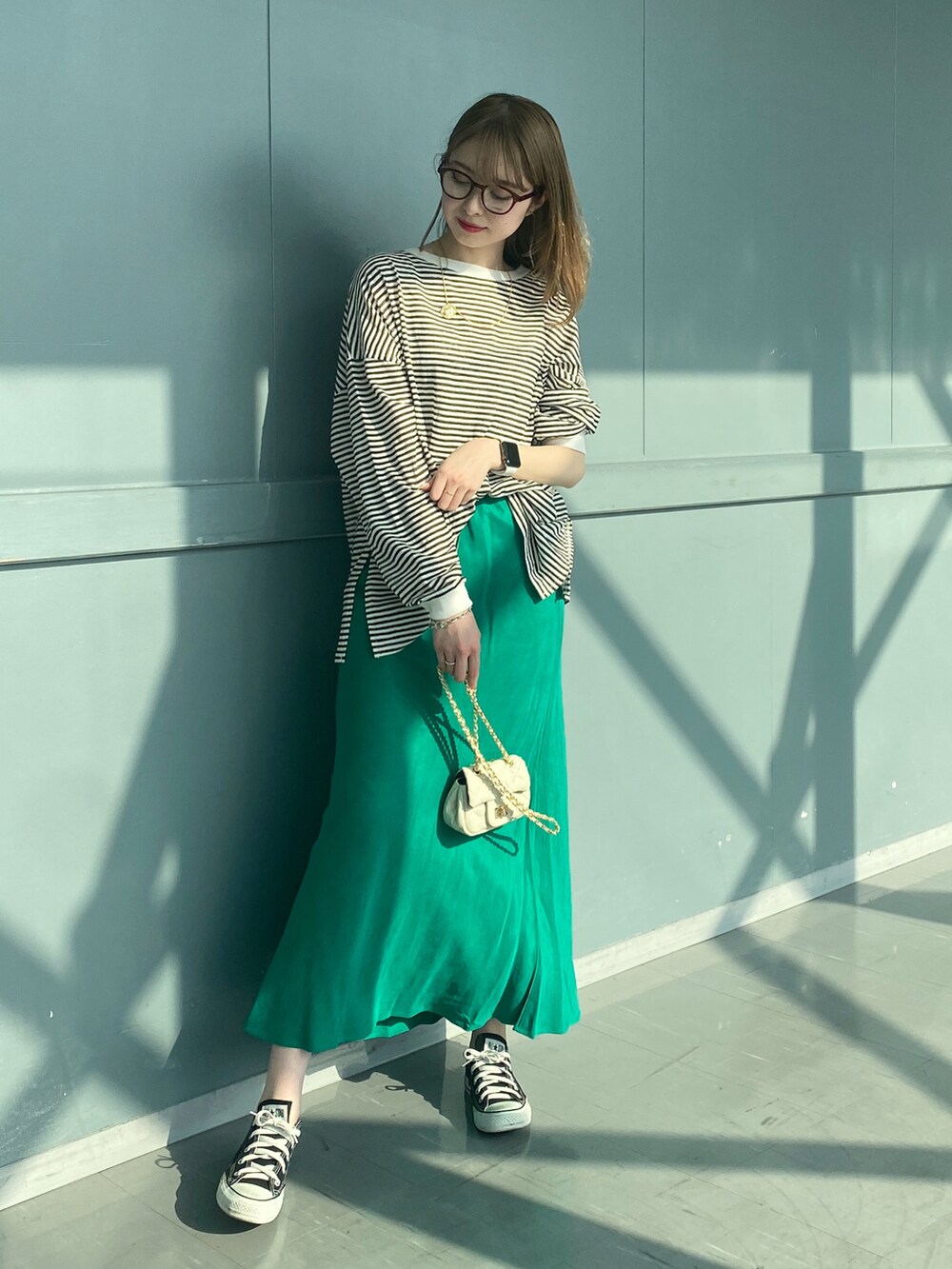 ブラック系のTシャツ/カットソー、グリーン系のスカート、ホワイト系のショルダーバッグを着用したレディースの春コーディネートの3枚目の写真