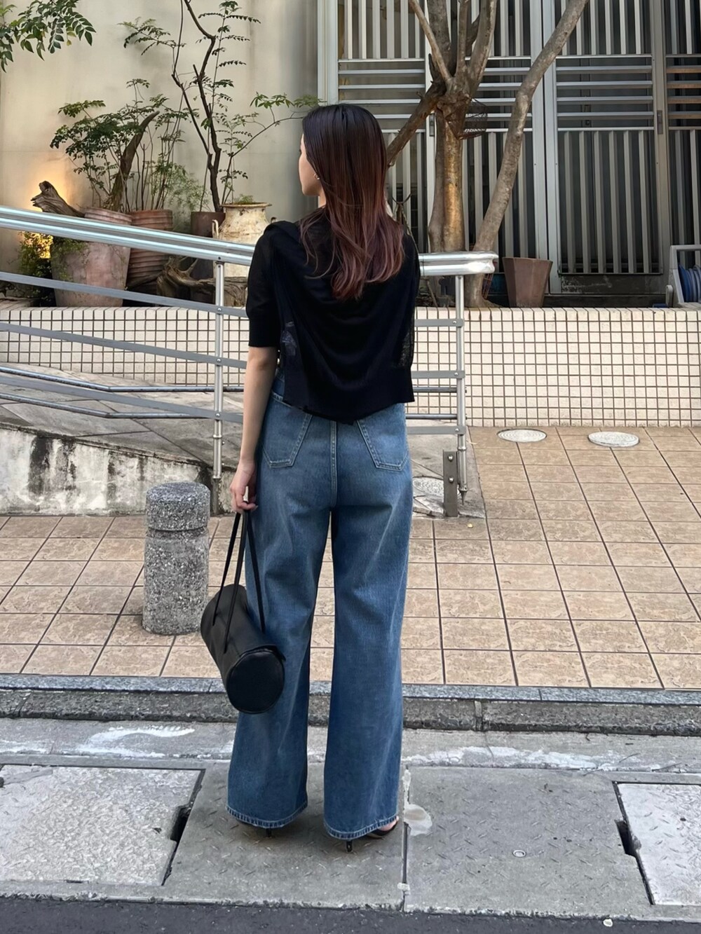 ブラック系のニット/セーター、ブラック系のカーディガン/ボレロ、ブルー系のデニムパンツを着用したレディースの春コーディネートの2枚目の写真