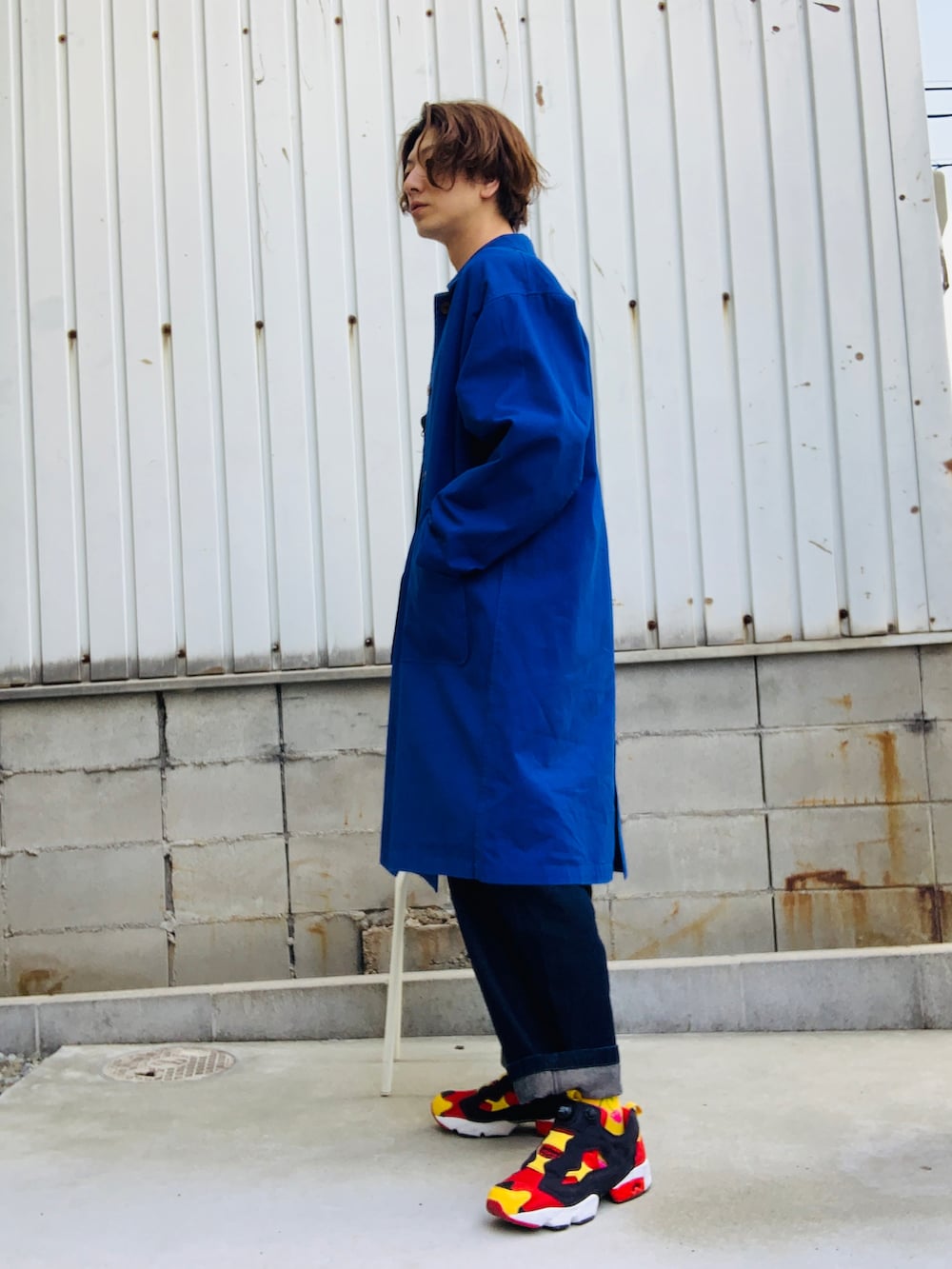 ブルー系のステンカラーコート、ブルー系のサロペット/オーバーオール、レッド系のスニーカーを着用したメンズの春コーディネートの3枚目の写真