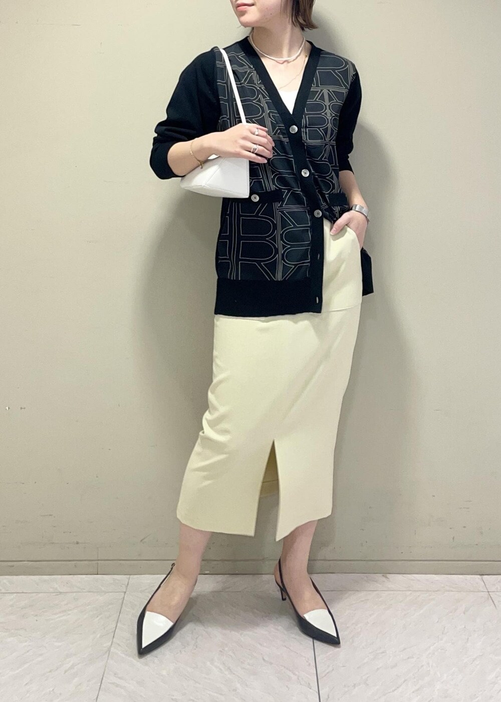 ブラック系のパンプス、ベージュ系のスカート、ブラック系のカーディガン/ボレロを着用したレディースの冬コーディネートの4枚目の写真