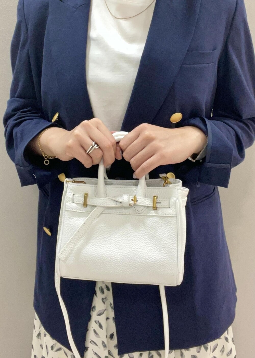 ホワイト系のハンドバッグ、ホワイト系のTシャツ/カットソー、ブルー系のテーラードジャケットを着用したレディースの夏コーディネートの6枚目の写真