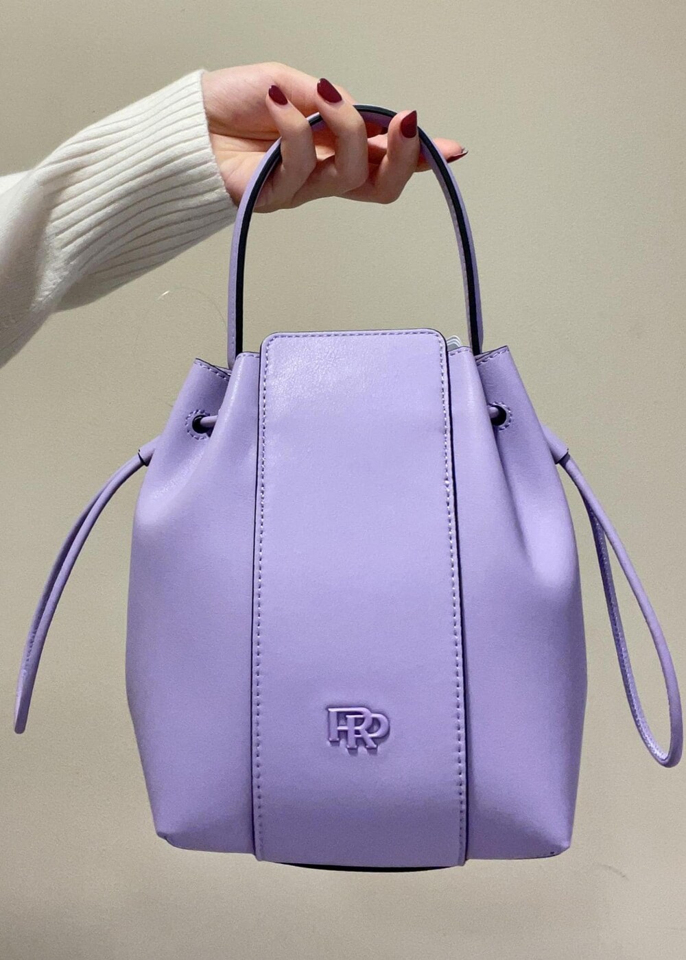 パープル系のハンドバッグ、ブラック系のブーツ、ブラック系のスカートを着用したレディースの秋コーディネートの9枚目の写真