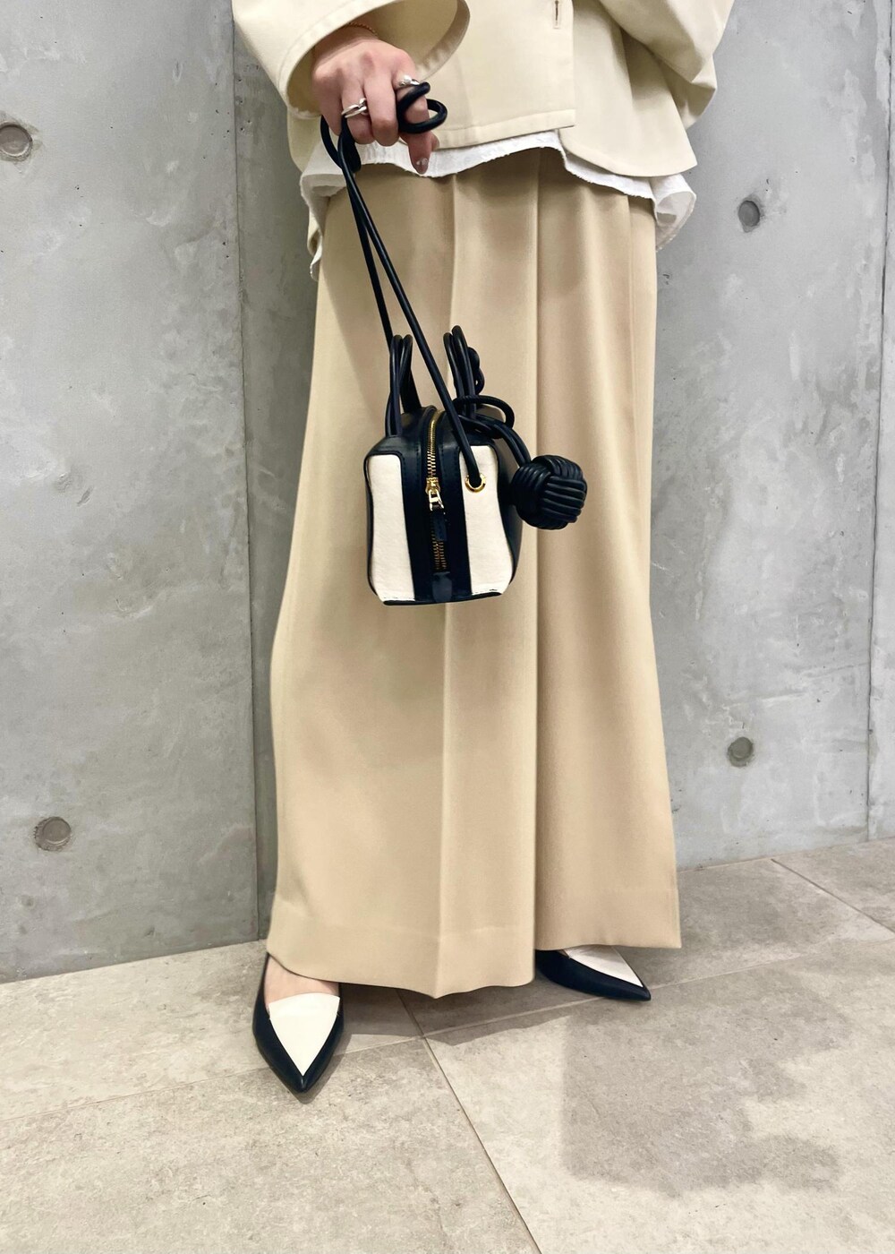 ブラック系のパンプス、ホワイト系のブルゾン、ブラック系のショルダーバッグを着用したレディースの春コーディネートの7枚目の写真