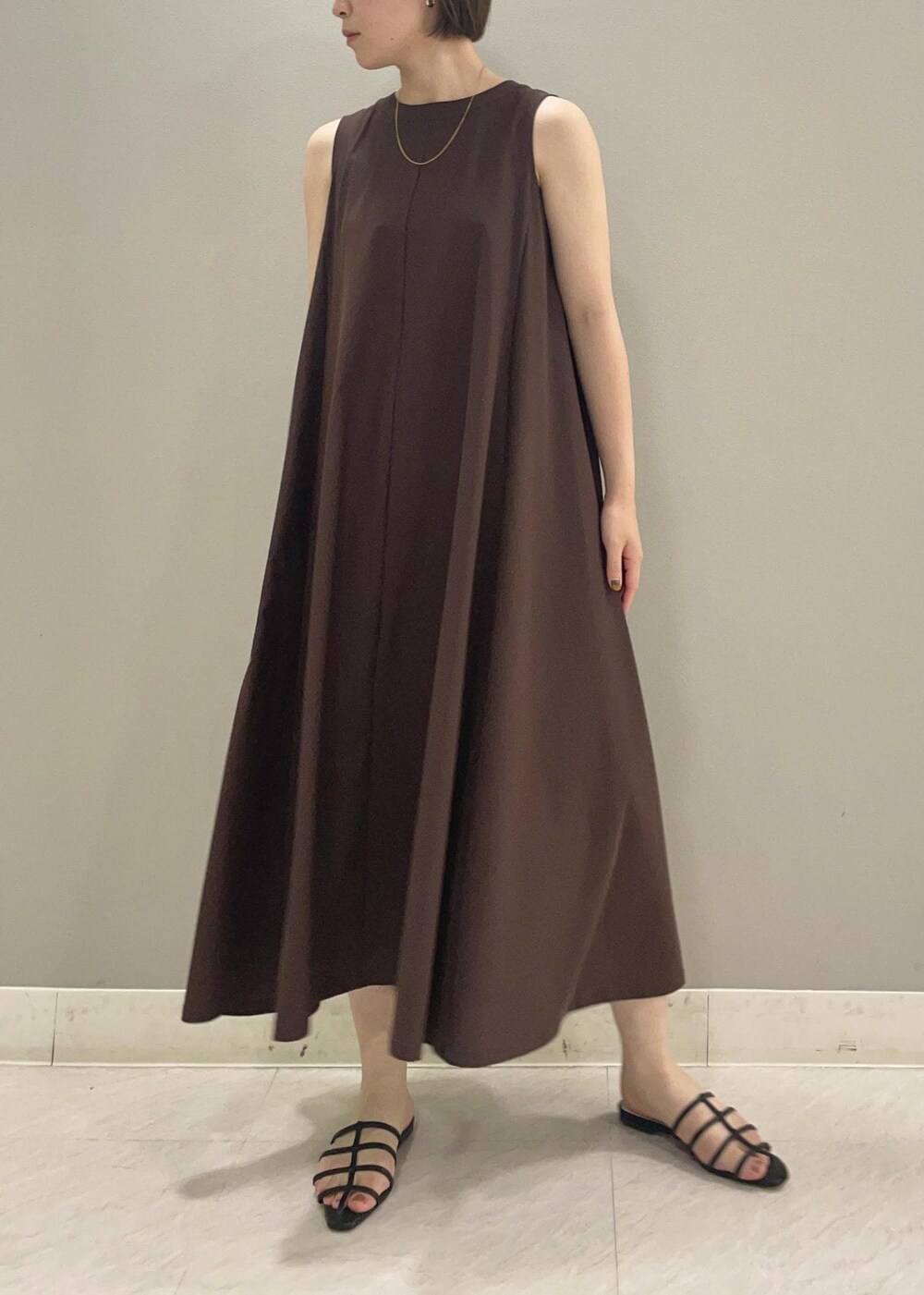 ブラック系のサンダル、ベージュ系のカーディガン/ボレロ、ブラウン系のワンピースを着用したレディースの夏コーディネートの5枚目の写真