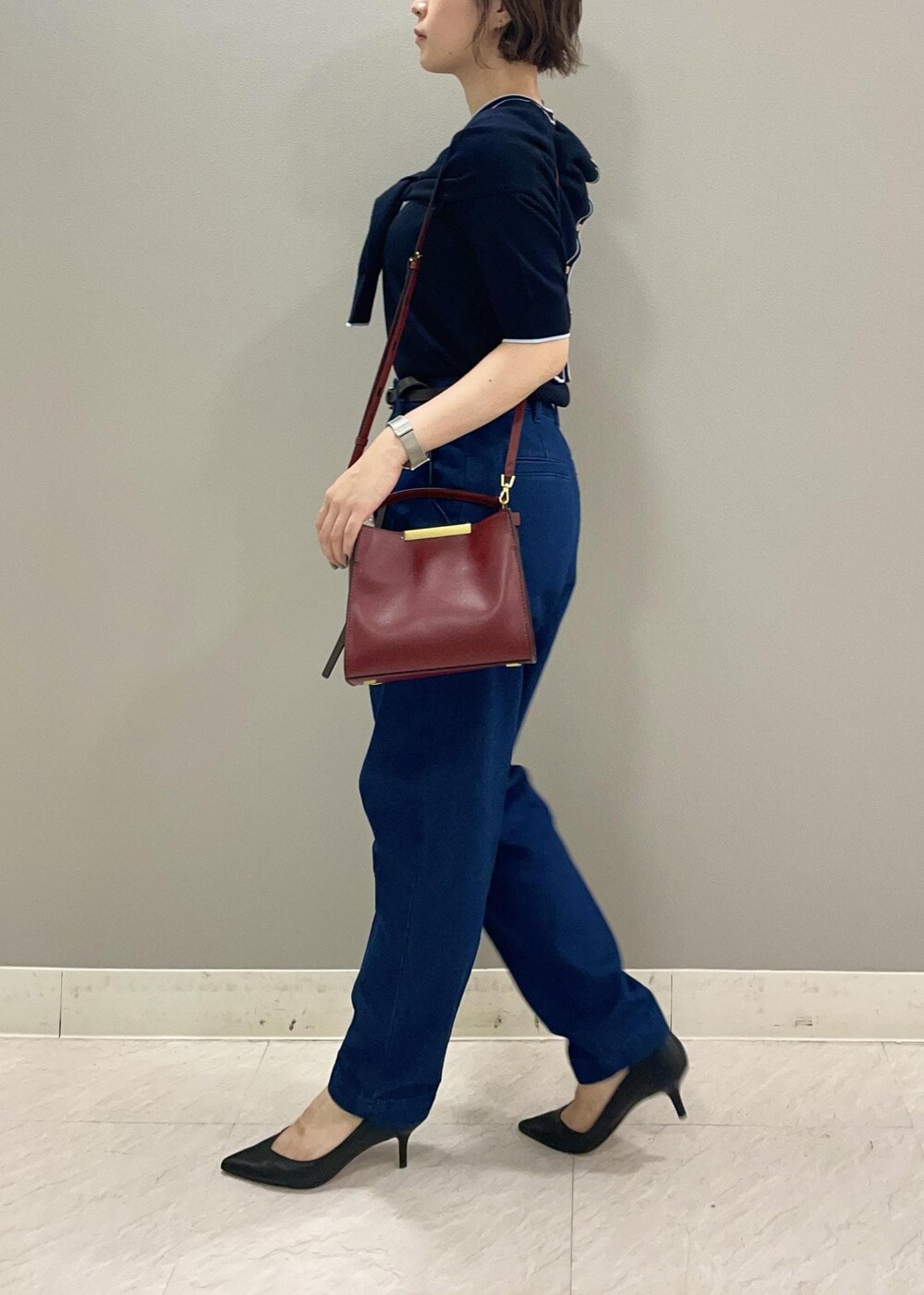 レッド系のショルダーバッグ、ブルー系のカーディガン/ボレロ、ブラック系のパンプスを着用したレディースの夏コーディネートの3枚目の写真