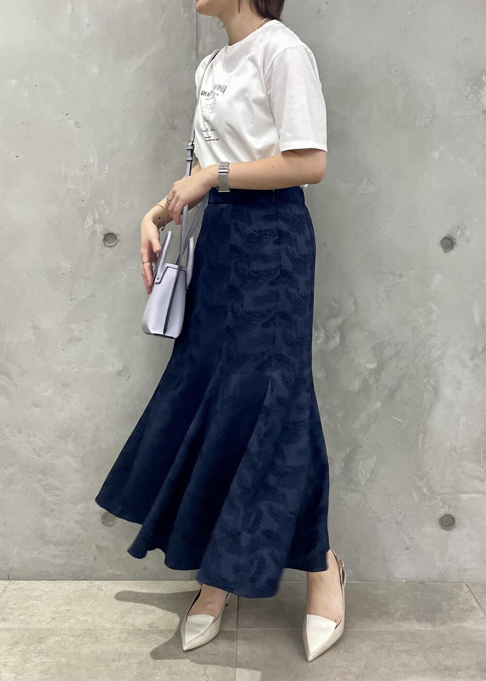 ベージュ系のパンプス、ブルー系のスカート、ホワイト系のTシャツ/カットソーを着用したレディースの春コーディネートの2枚目の写真