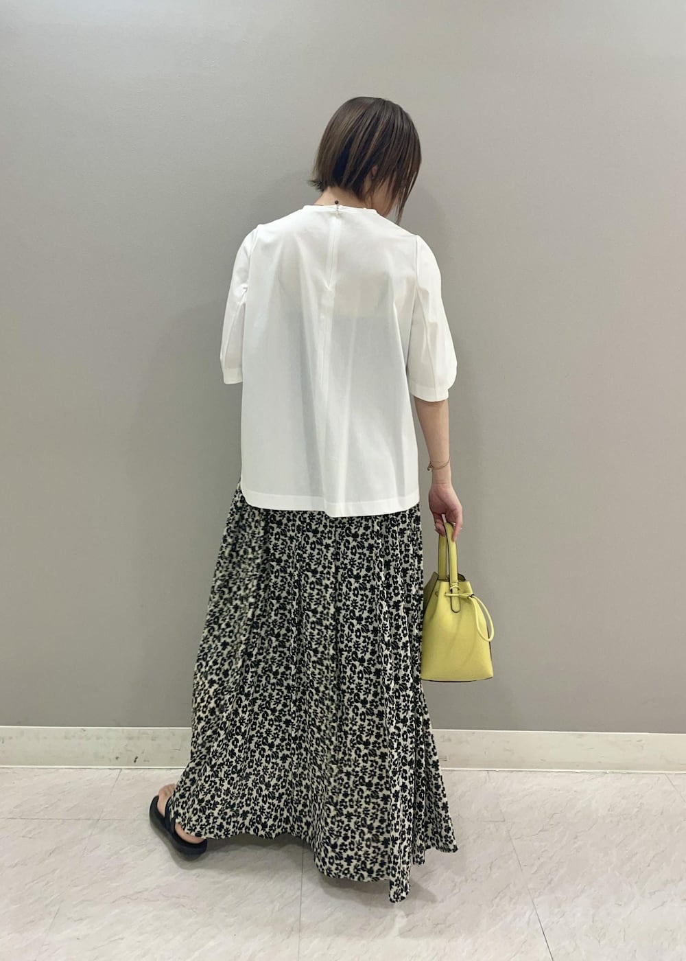 ベージュ系のハンドバッグ、ホワイト系のTシャツ/カットソー、ブラック系のスカートを着用したレディースの夏コーディネートの3枚目の写真