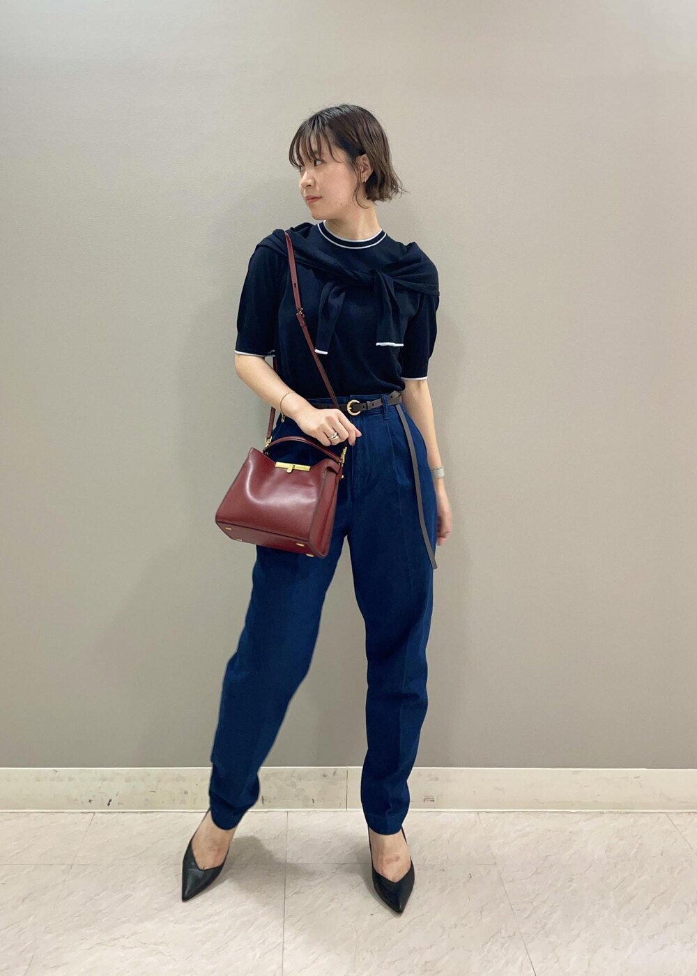 レッド系のショルダーバッグ、ブルー系のカーディガン/ボレロ、ブラック系のパンプスを着用したレディースの夏コーディネートの2枚目の写真