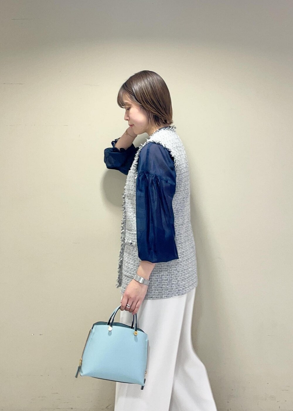 ブラック系のパンプス、ブルー系のハンドバッグ、ブラック系のベストを着用したレディースの冬コーディネートの3枚目の写真