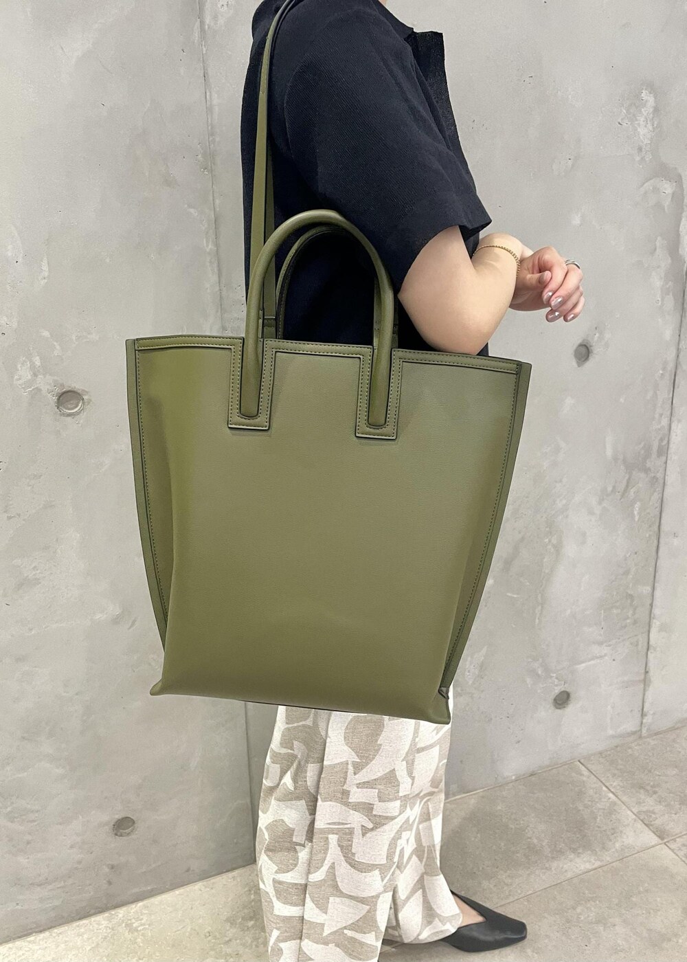 グリーン系のトートバッグ、ブラック系のパンプス、ブルー系のニット/セーターを着用したレディースの春コーディネートの10枚目の写真