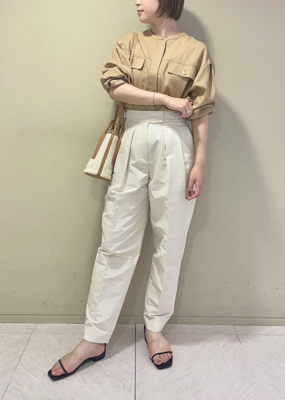 ブラック系のサンダル、ベージュ系のハンドバッグ、ホワイト系のその他パンツを着用したレディースの夏コーディネートの3枚目の写真