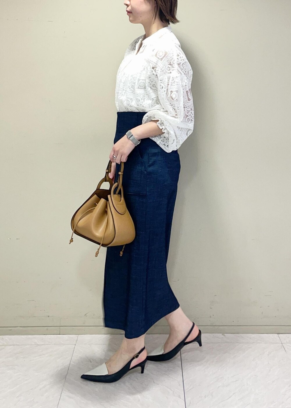 イエロー系のショルダーバッグ、ブルー系のスカート、ブラック系のパンプスを着用したレディースの冬コーディネートの5枚目の写真