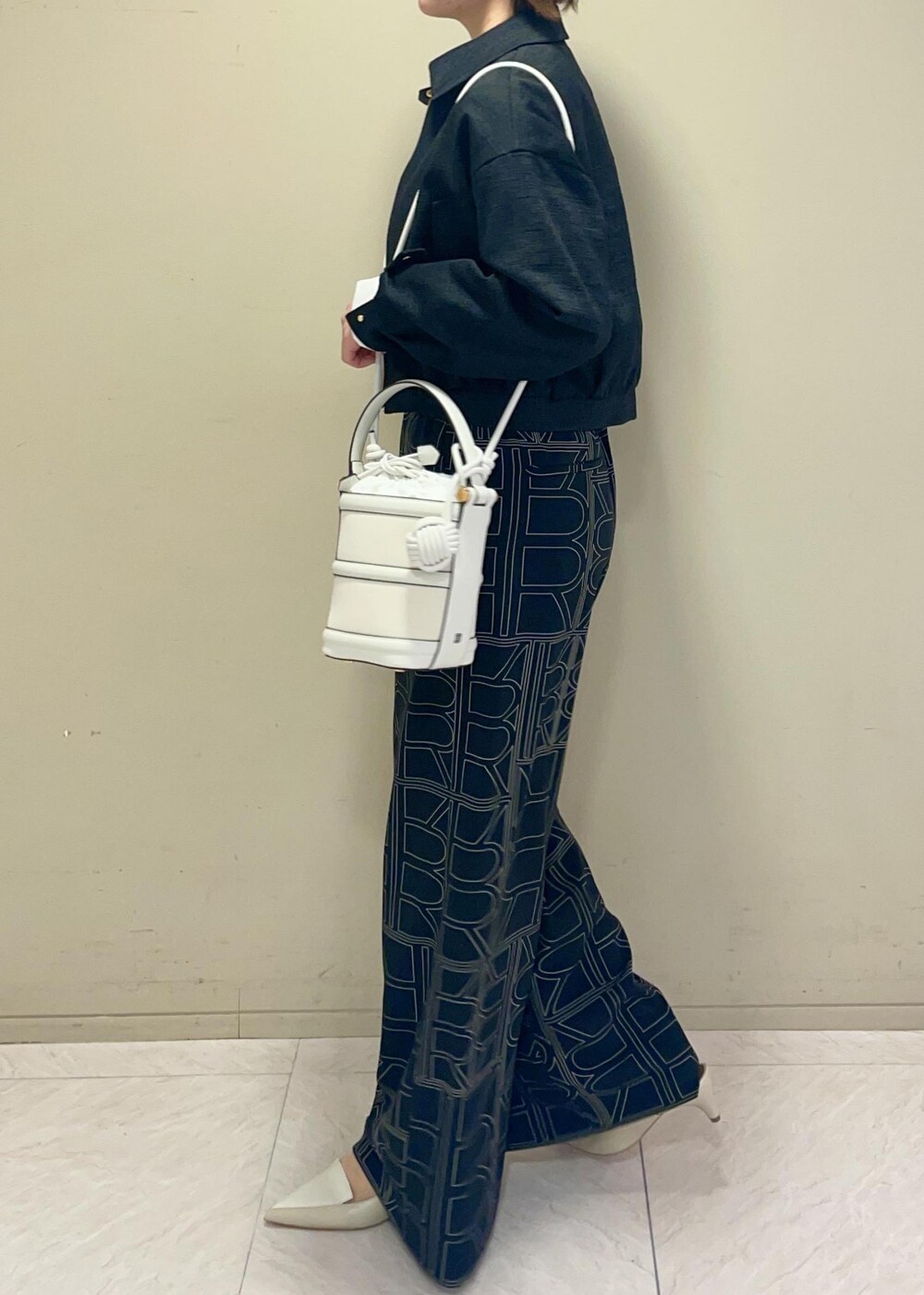 ホワイト系のハンドバッグ、ブラック系のその他パンツ、ブラック系のブルゾンを着用したレディースの冬コーディネートの4枚目の写真