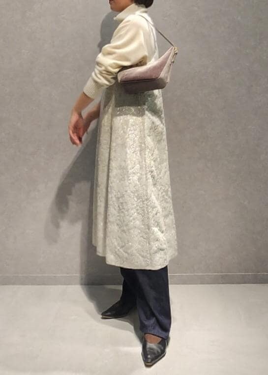 ブルー系のデニムパンツ、グレー系のハンドバッグ、ホワイト系のワンピースを着用したレディースの冬コーディネートの2枚目の写真