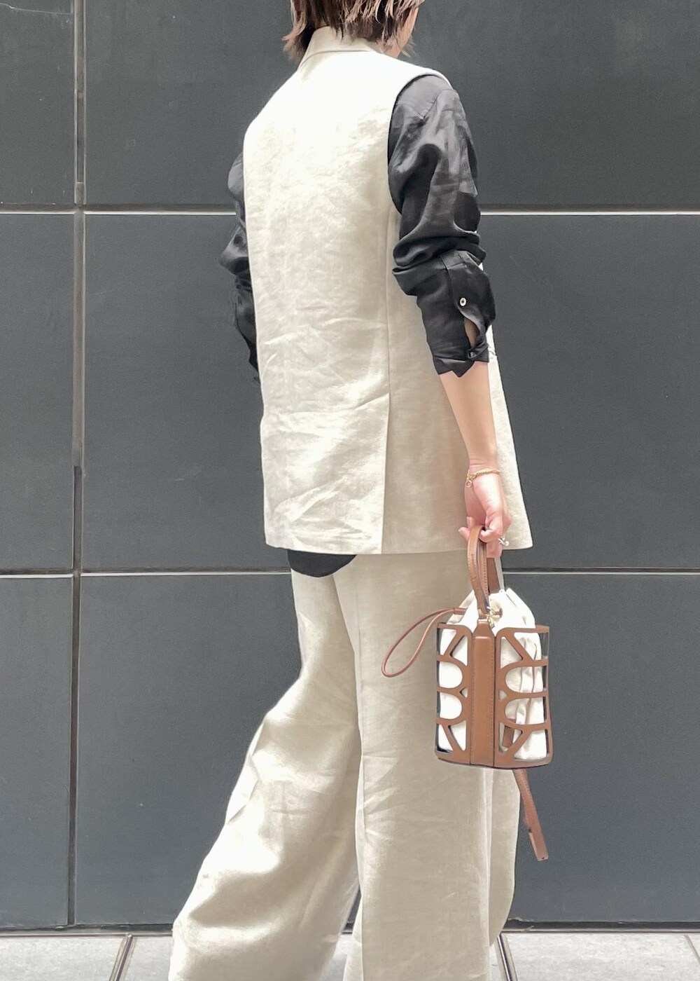 ブラック系のパンプス、ブラック系のシャツ/ブラウス、ベージュ系のベストを着用したレディースの春コーディネートの4枚目の写真